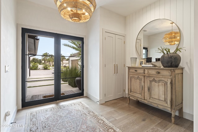 doorway featuring french doors, light wood-style flooring, and baseboards