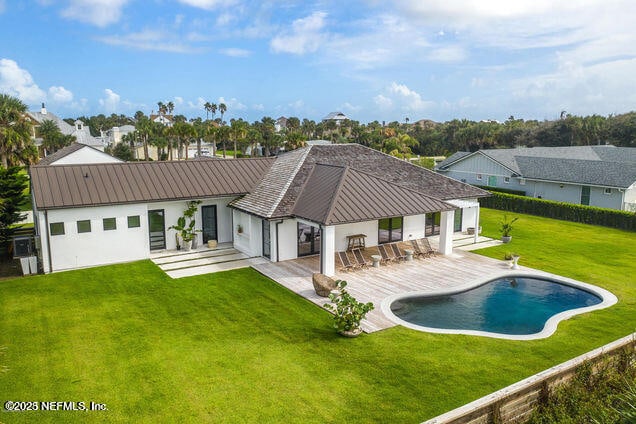 back of property with metal roof, a patio, a yard, an outdoor pool, and a standing seam roof