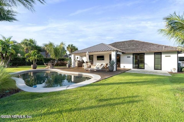 back of property featuring metal roof, a yard, an outdoor pool, a standing seam roof, and a patio area