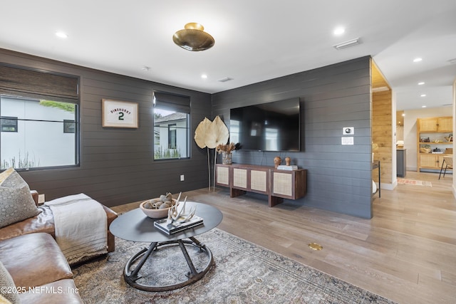 living area with visible vents, wooden walls, light wood-style flooring, and recessed lighting