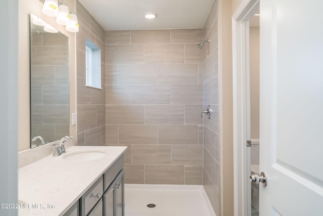 bathroom featuring tiled shower and vanity