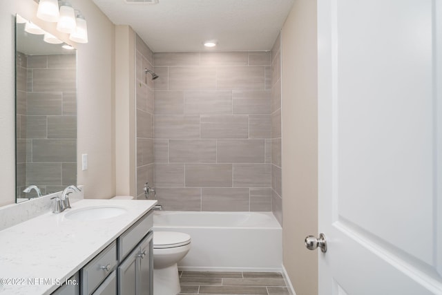 full bathroom with tiled shower / bath, vanity, and toilet