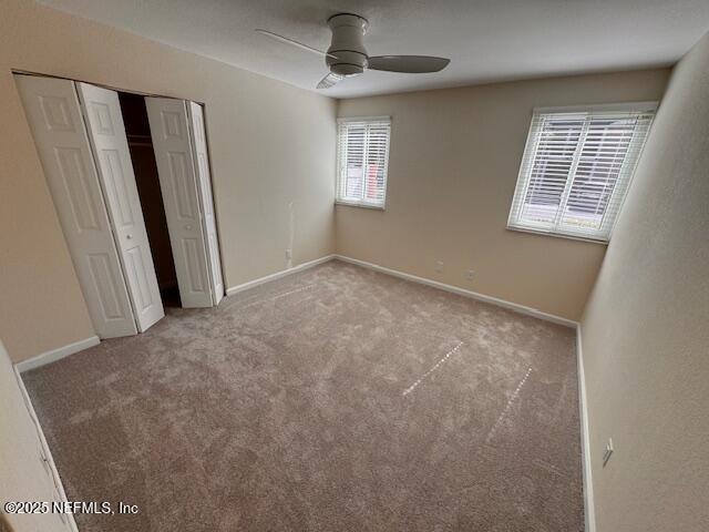 unfurnished bedroom with ceiling fan, a closet, and light carpet