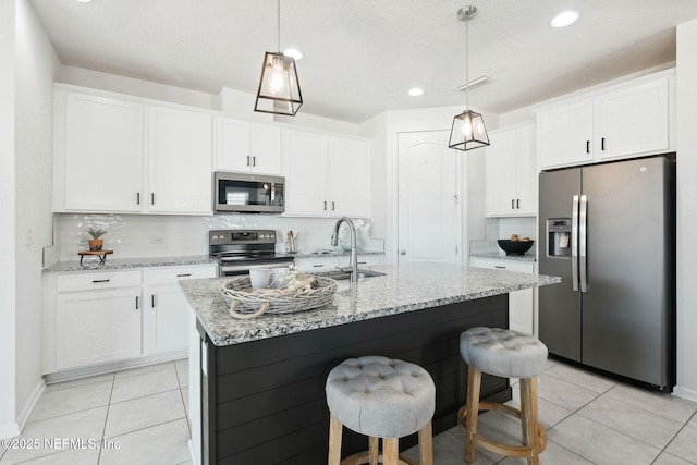 kitchen with white cabinetry, stainless steel appliances, sink, and a center island with sink