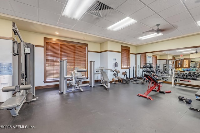 exercise room with a drop ceiling and ceiling fan