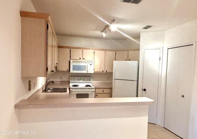 kitchen featuring sink, light tile patterned floors, white appliances, and kitchen peninsula