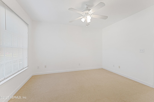 spare room with light carpet, ceiling fan, and baseboards