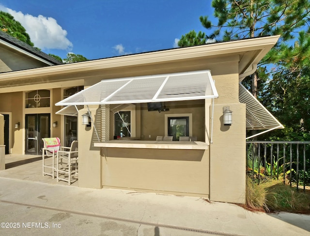 doorway to property with a patio, outdoor dry bar, and stucco siding