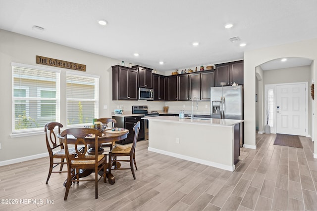 kitchen featuring a kitchen island with sink, sink, dark brown cabinetry, and appliances with stainless steel finishes