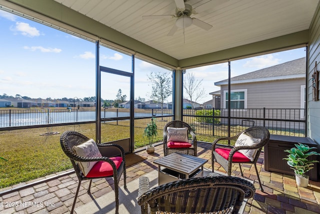 sunroom with ceiling fan and a water view