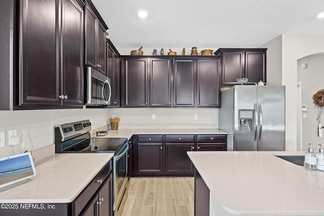 kitchen featuring stainless steel appliances, dark brown cabinets, sink, and a textured ceiling