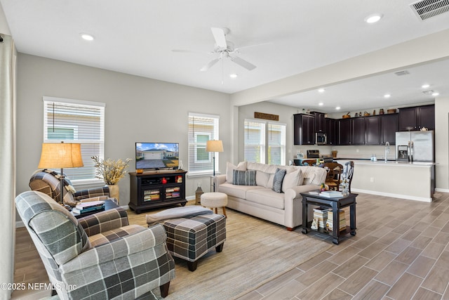 living room with sink, ceiling fan, and light wood-type flooring