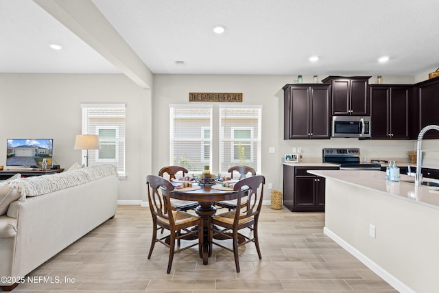 kitchen with appliances with stainless steel finishes, sink, a wealth of natural light, and dark brown cabinetry