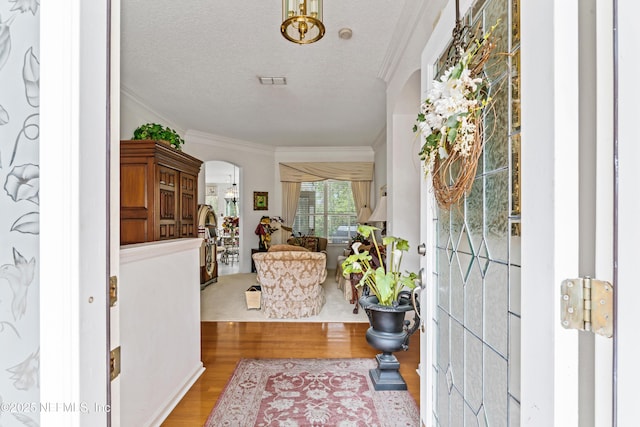 entryway with crown molding, a textured ceiling, and hardwood / wood-style floors