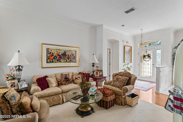 living room with a textured ceiling, ornamental molding, and light hardwood / wood-style floors