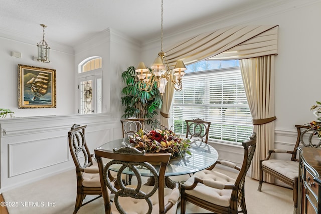 carpeted dining space featuring a chandelier and ornamental molding