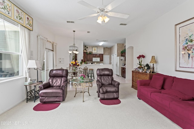 living room with ceiling fan with notable chandelier and carpet flooring