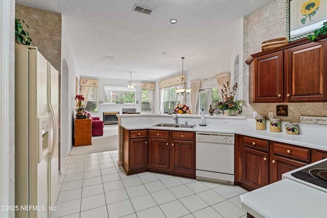 kitchen featuring white appliances, sink, a textured ceiling, decorative light fixtures, and kitchen peninsula