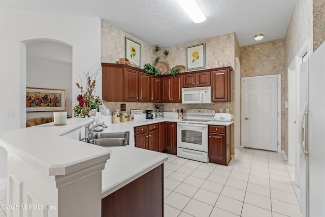 kitchen with white appliances, a textured ceiling, light tile patterned floors, sink, and kitchen peninsula