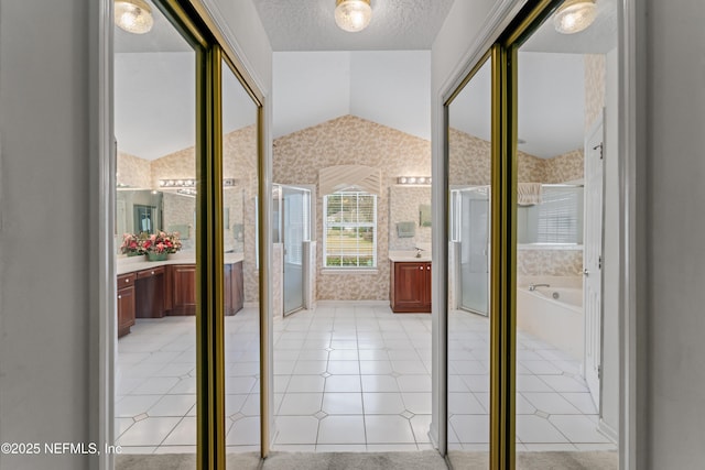 entryway with a textured ceiling, vaulted ceiling, and light tile patterned floors