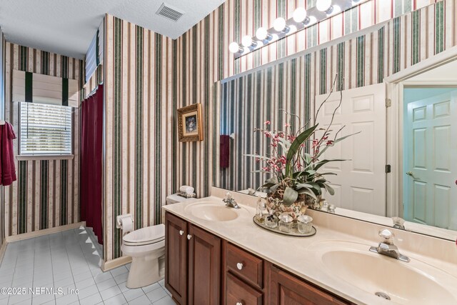 bathroom with a textured ceiling, toilet, vanity, and tile patterned flooring