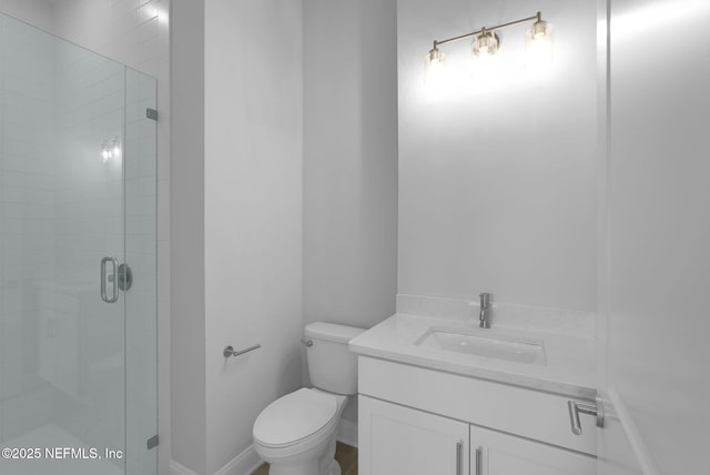 bathroom featuring vanity, a shower with door, and toilet