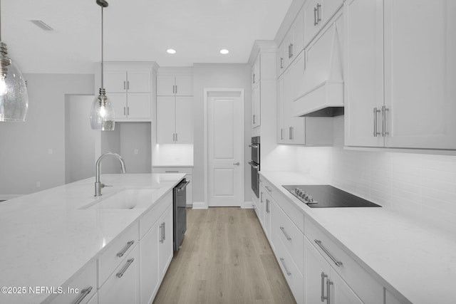 kitchen featuring sink, custom exhaust hood, white cabinetry, hanging light fixtures, and stainless steel appliances