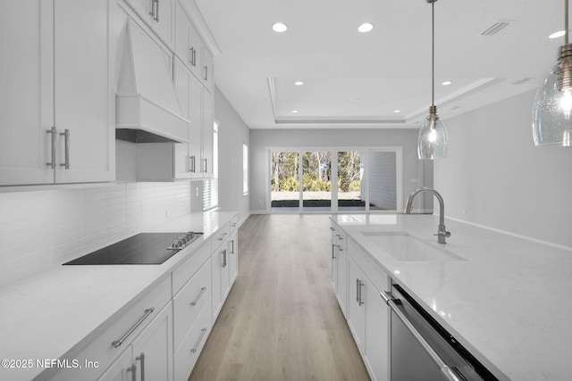 kitchen with sink, black electric cooktop, a tray ceiling, pendant lighting, and white cabinets