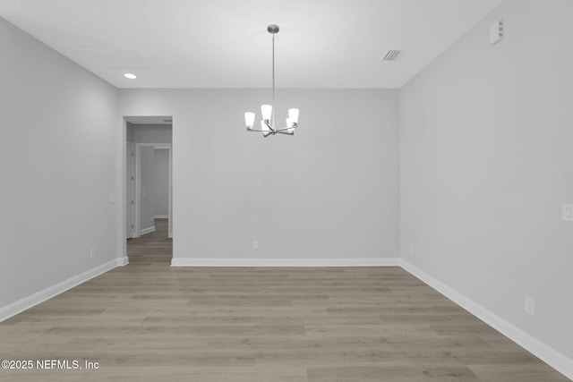 unfurnished dining area featuring an inviting chandelier and light hardwood / wood-style flooring