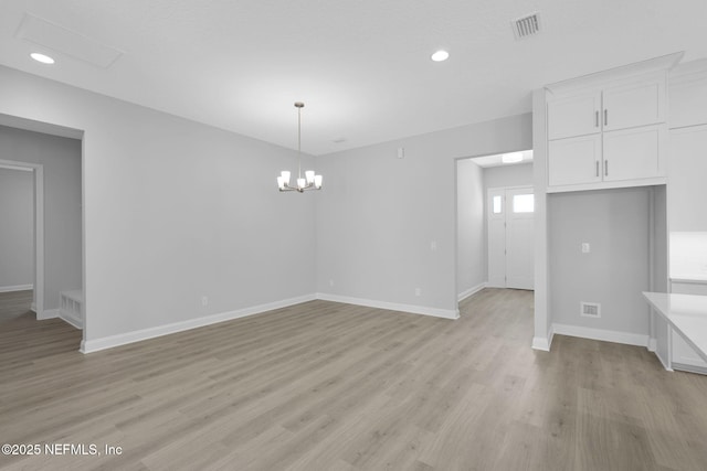 unfurnished dining area featuring an inviting chandelier and light wood-type flooring