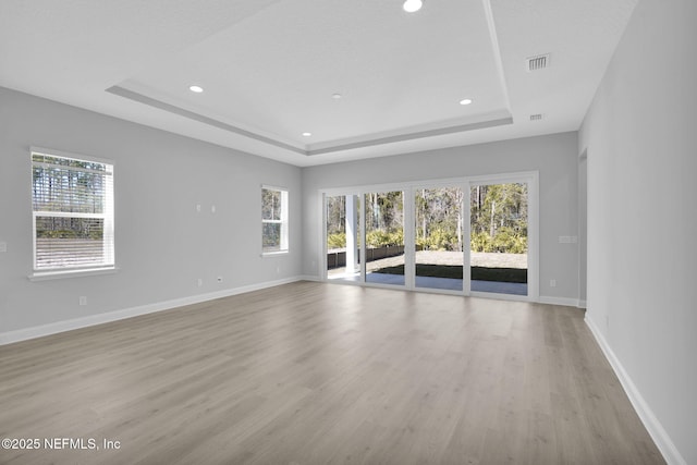 unfurnished living room with light hardwood / wood-style flooring and a tray ceiling