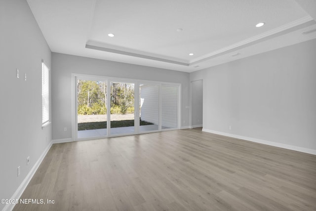 unfurnished room with light hardwood / wood-style floors and a tray ceiling