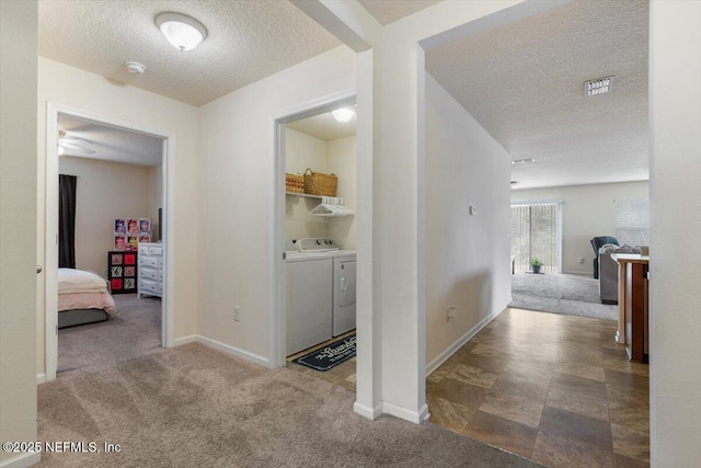 hallway with washing machine and clothes dryer, carpet flooring, and a textured ceiling