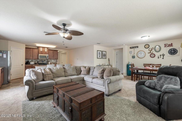 carpeted living room featuring ceiling fan and a textured ceiling