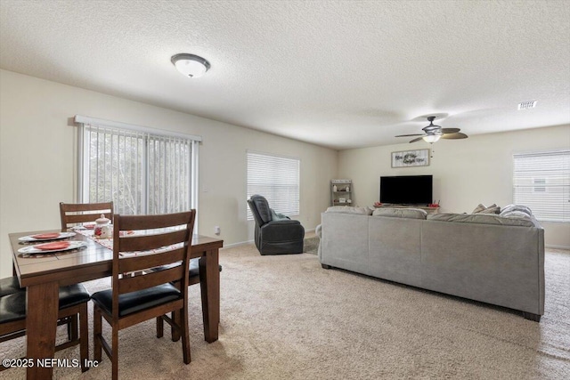 carpeted dining space with ceiling fan and a textured ceiling