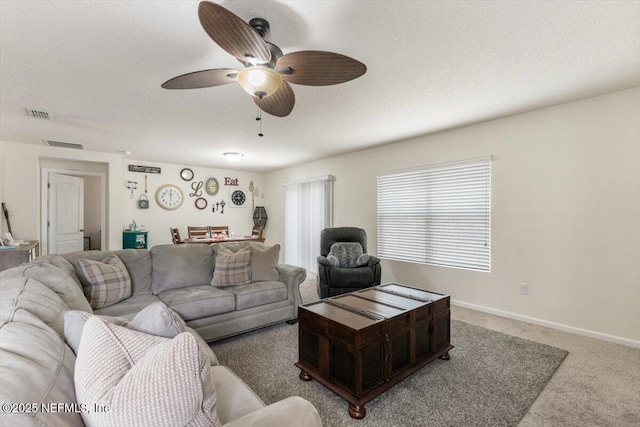 carpeted living room with ceiling fan and a textured ceiling