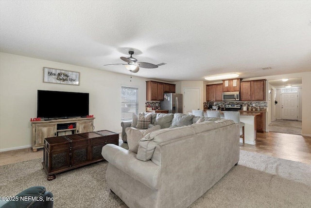 living room with ceiling fan, light carpet, and a textured ceiling