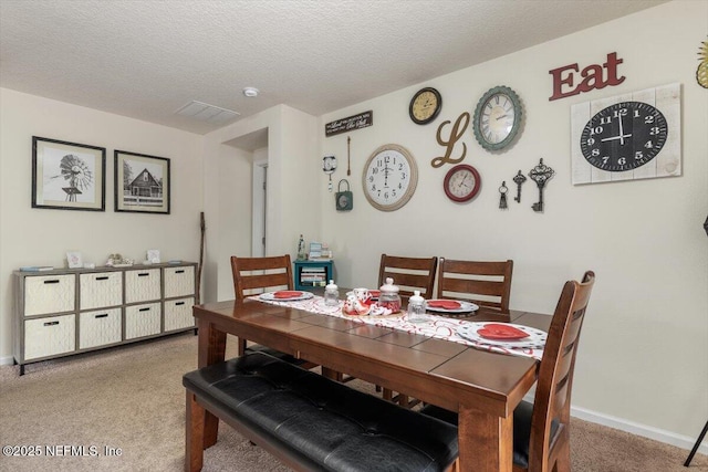 carpeted dining space with a textured ceiling