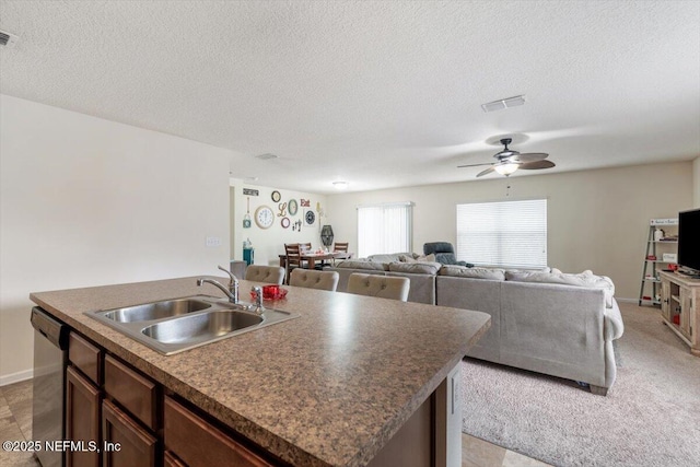 kitchen with sink, a textured ceiling, dishwasher, an island with sink, and ceiling fan