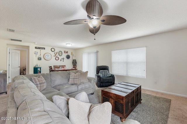 carpeted living room featuring ceiling fan and a textured ceiling