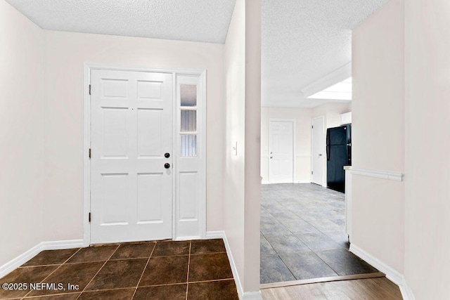 entryway with a textured ceiling and dark tile patterned floors