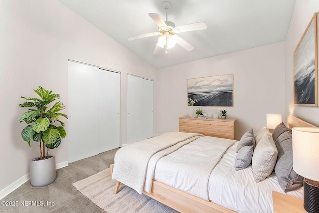 bedroom featuring multiple closets, lofted ceiling, carpet flooring, and ceiling fan