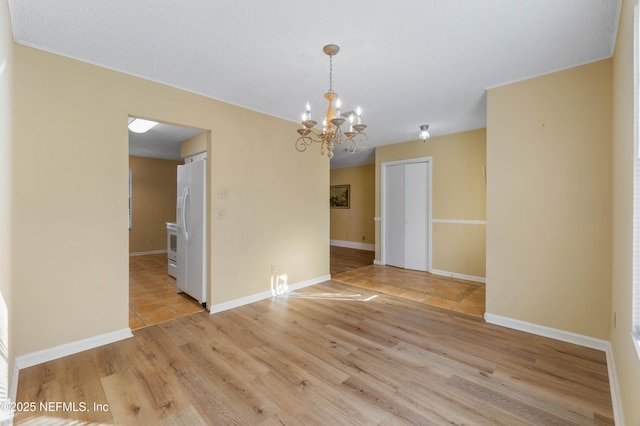 spare room featuring a chandelier and light wood-type flooring