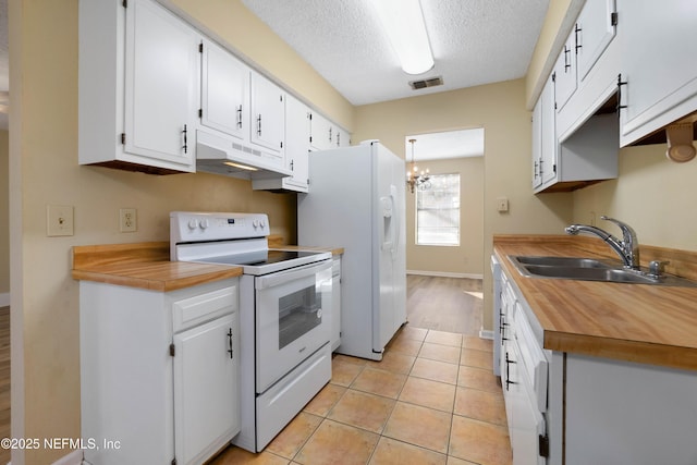 kitchen featuring sink, white appliances, light tile patterned floors, white cabinetry, and a textured ceiling