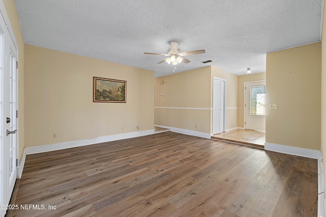 empty room featuring ceiling fan, hardwood / wood-style flooring, and a textured ceiling