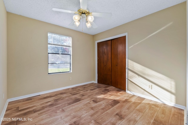 unfurnished bedroom featuring hardwood / wood-style flooring, ceiling fan, a textured ceiling, and a closet