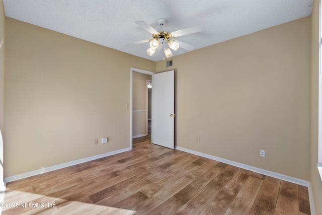 spare room featuring ceiling fan, light hardwood / wood-style flooring, and a textured ceiling