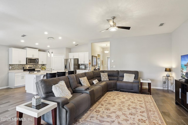 living room featuring vaulted ceiling, sink, ceiling fan, and light hardwood / wood-style floors