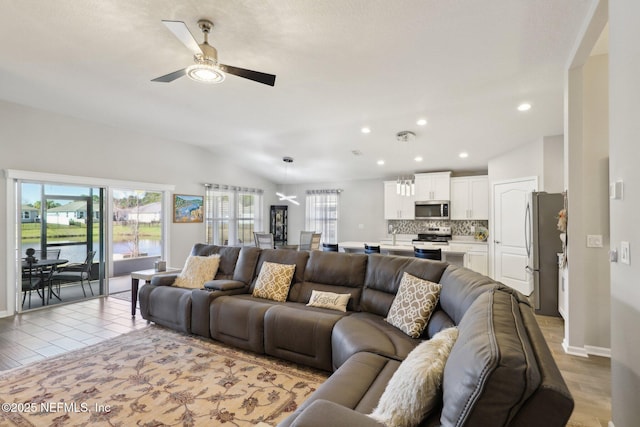 living room with lofted ceiling, ceiling fan, and light wood-type flooring