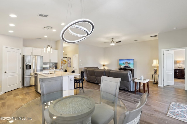 dining area with ceiling fan, sink, and light hardwood / wood-style flooring